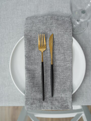Grey napkin on a white plate. Table setting. Fork and a knife.