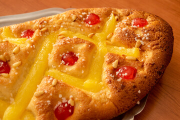 Close-up view of "Coca de Sant Joan" with cream, candied cherries and pine nuts, a festive Catalan sweet typical of the Saint John's Eve celebration