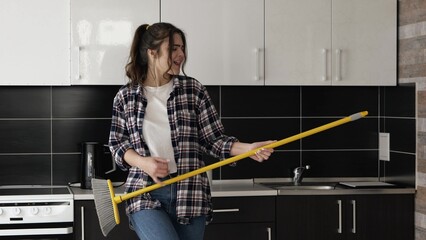 Young woman in kitchen during quarantine. Stand alone and pretend to play on mos as on guitar. Have...