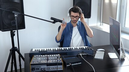 Young man in sound recording studio. Male video blogger filming hot to work with mixing console and...