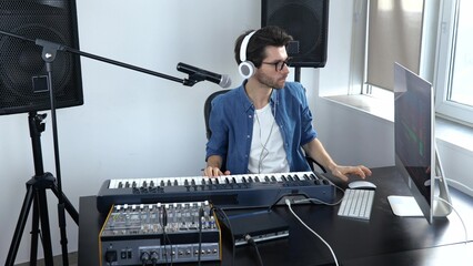 Young man in sound recording studio. Slow motion of cheerful soundman adjusting music console....