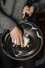 Diligent woman housewife washes, cleans with yellow sponge and detergent with foam dirty teflon...