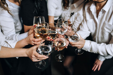 Close-up photo of many hands of girls, girlfriends at a bachelorette party, celebration with glasses of alcohol, champagne, wine.