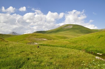 mountain landscape with blue sky and clouds, green grass, tour of the Ecrins and Oisans Massif, hiking, trek, GR54, Alps, France