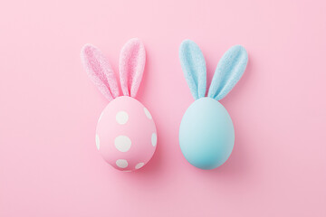 Obraz premium Easter eggs and bunny ears on a pastel pink background with copy space