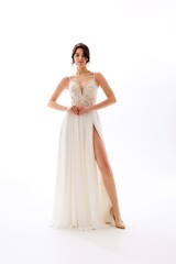 Elegant model showcasing a beautiful bridal gown with intricate detailing and a thigh-high slit in a pristine studio setting