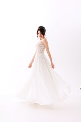 Elegant bride twirls in a flowing white dress against a soft, minimalist backdrop during a bridal photoshoot
