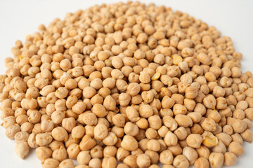 Many chickpeas scattered on a white background, isolated, top view, raw uncooked legumes, healthy organic food, high-protein vegetarian ingredient, nutritious dried peas, agriculture harvest