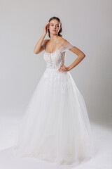 Fototapeta premium Elegant bridal gown showcased by model in minimalist studio setting during daytime