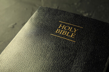 Hardcover Holy Bible in English language on black table, closeup