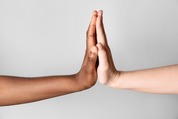 Stop racism. People of different skin colors giving high five on light grey background, closeup