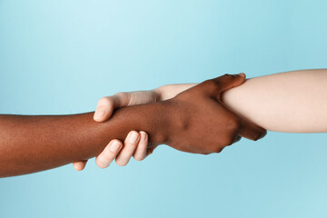 Stop racism. People of different skin colors holding hands on light blue background, closeup