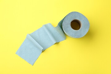 Light blue toilet paper roll on yellow background, top view