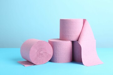 Pink toilet paper rolls on light blue background