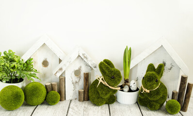 Easter decorative composition, home decoration for the bright Easter holiday. On a light background, cute rabbits and wooden houses, front view, floral style.