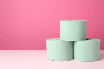 Green toilet paper rolls on pink background. Space for text