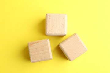 Blank wooden cubes on yellow background, flat lay