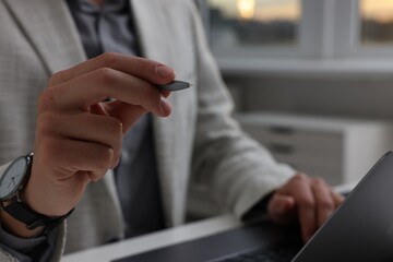 Electronic signature. Man with stylus and laptop at table indoors, closeup