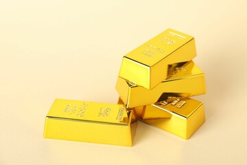Shiny gold bars on beige background, closeup