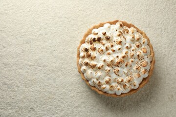 Delicious meringue pie on beige textured table, top view. Space for text