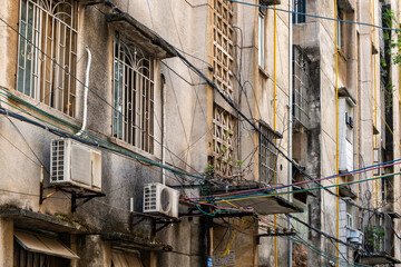 Weathered exterior of an old walkup apartment building in Liuzhou, China with a tangle of...