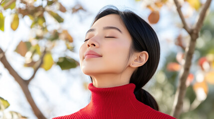 Malay woman in red ribbed necks closed eyes enjoy fresh air in park with cherry blossom