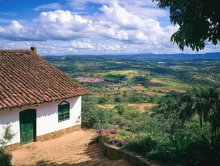 Fototapeta premium Rural brick house with terra cotta roof tiles overlooking green mountains and valleys, under blue sky.