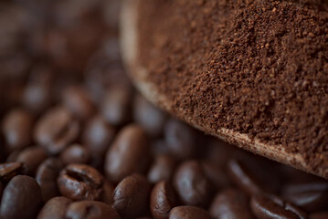 Roasted coffee beans and coffee powder on a wooden table. Wooden spoon with ground coffee inside.