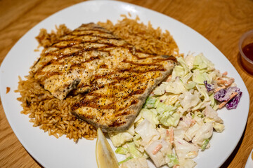 Grilled fish with cajun seasoning, coleslaw, and seasoned rice served at a Hawaiian seafood restaurant