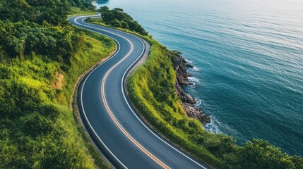 An aerial view showcasing a curved asphalt road winding along a picturesque coastline, with the ocean or sea in the background.
