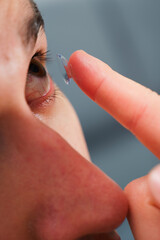 Correcting eye wellnesses with optical contact lenses. Man inserts a contact lens into eye for...