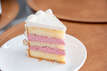 A slice of vanilla and raspberry layered cake with whipped frosting on a white plate