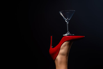 Elegant balancing act showcasing red high heel and martini glass against dark background