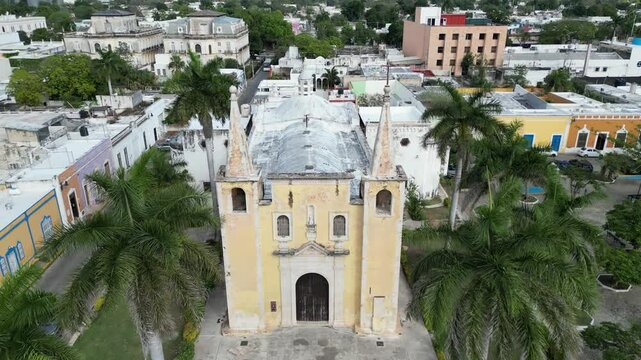 view of historic santa ana church in merida yucatan mexico (yellow colonial beautiful spanish architecture) with mansions on paseo de montejo in background (travel tourism destination latin america)