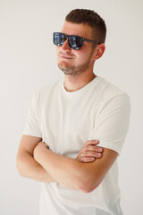 Fototapeta premium A confident young man wearing stylish sunglasses poses against a simple yet vibrant background