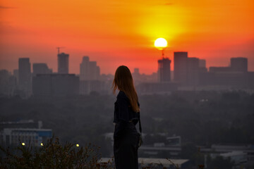 Fototapeta premium Young woman Watching Sunset Over the City Skyline
