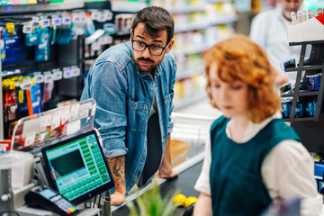 Impatient customer waiting at supermarket checkout,