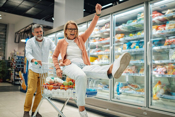 Senior couple having fun while shopping in supermarket,