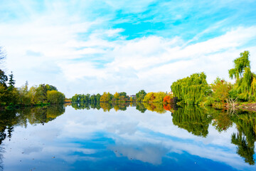 Reflections of autumn foliage on a calm lake with blue sky