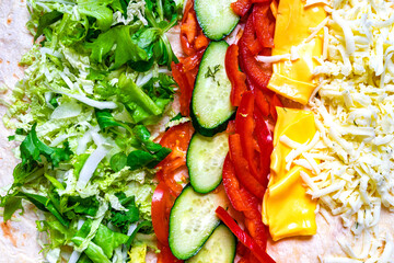 Colorful fresh vegetables arranged on a tortilla for a wrap