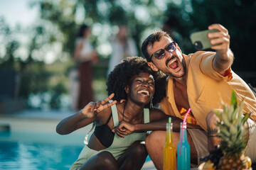 Friends taking selfie by the pool during summer party