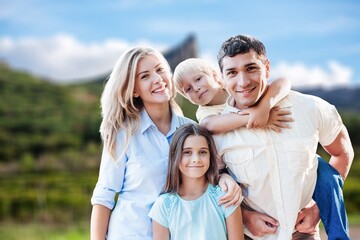 Obraz premium Happy young family with children at nature park background