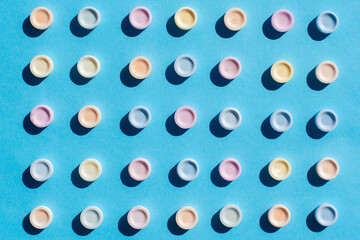 Top view of edible tablets of different colors. Sugar tablets on blue background.