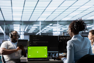 Team of programmers in server farm using green screen laptop, looking for misconfigurations....