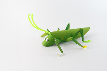 Cardboard tube grasshopper model with bent legs made from small cardboard pieces and pipe cleaner accents. An imaginative and colorful craft project, turning simple materials into fun art,