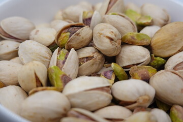 Roasted pistachios showing green and purple hues filling a bowl