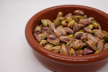 Shelled pistachios filling a small terracotta bowl