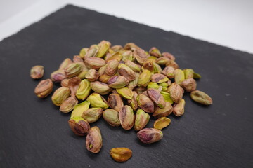 Pistachios resting on a dark slate surface
