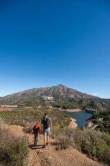 Obraz premium Father and son hiking in scenic mountain landscape under clear blue sky, La Concepcion reservoir in Marbella