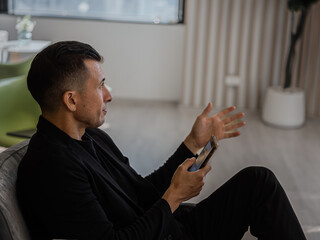 Businessman Sitting on Sofa Using Smartphone for Communication
